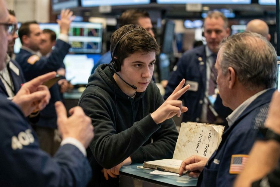 Teen trader making hand signals in a crowded open-outcry trading pit during a first trade